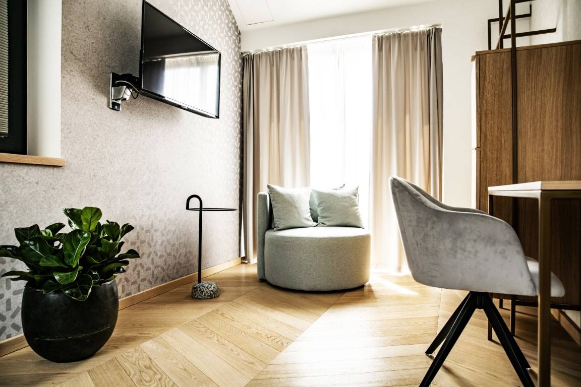 Bazilika Suite nappali része televízióval, kerek fotellel és cserepes növénnyel